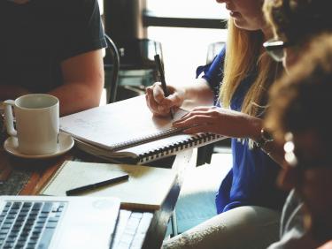 Tisch mit Studenten und Unterrichtsmaterial